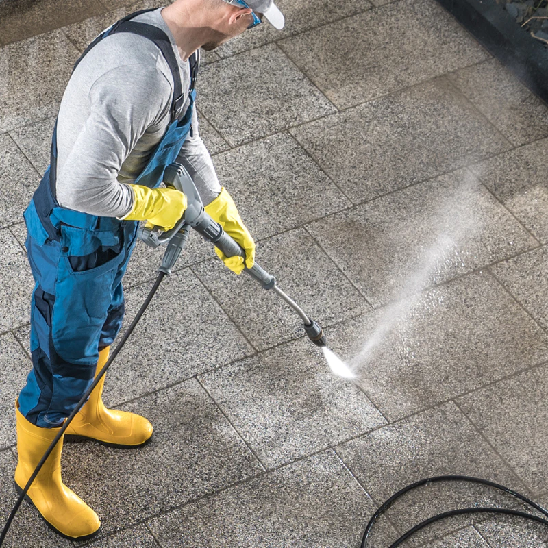 top view of a man pressure washing the concrete driveway